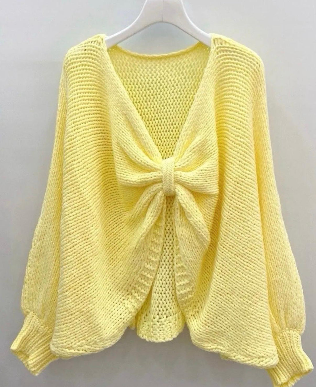 Damen Strickpullover mit Schleife in Buttergelb, grob gestrickt mit langen Ärmeln und großer Schleife am offenen Rücken.